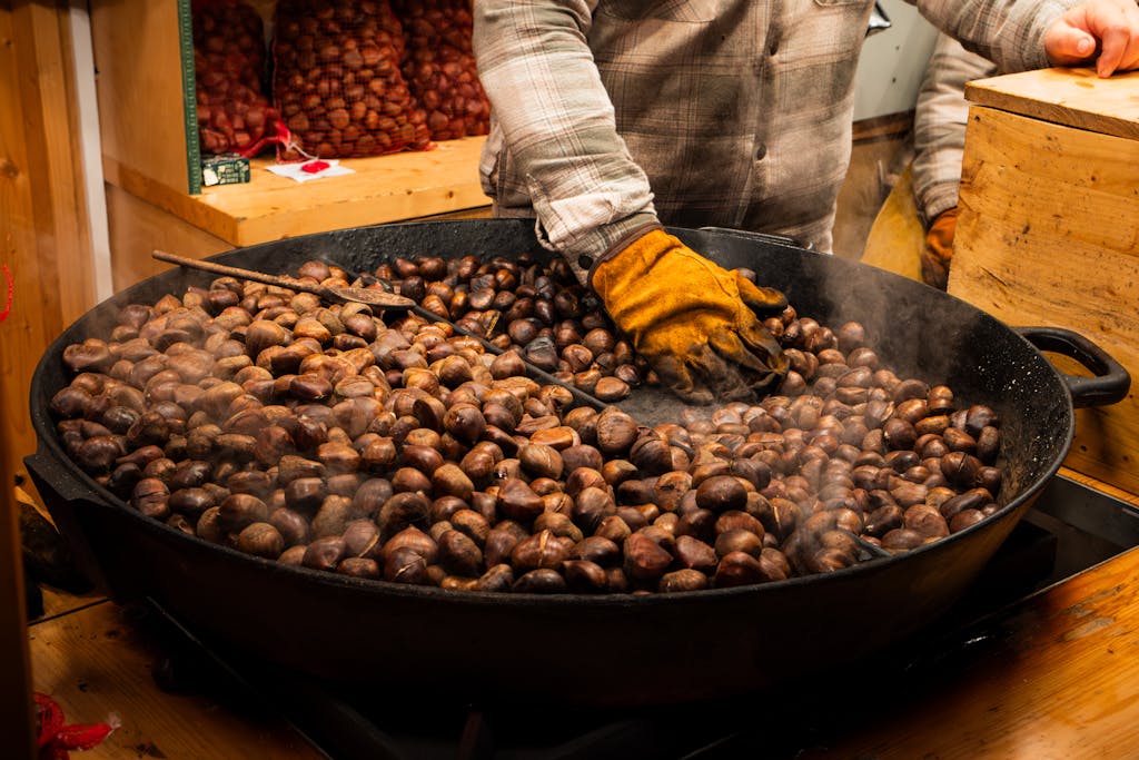 A person roasting chestnuts at a festive Christmas market in Düsseldorf, Germany.